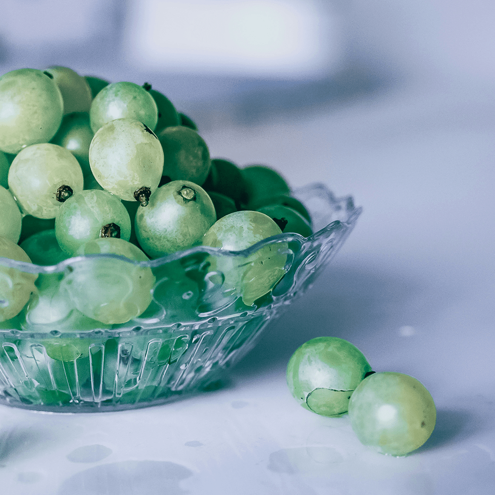 Bowl of green grapes next to a chocolate fountain.