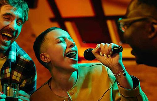Person singing karaoke with a microphone under club lights.