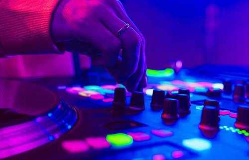 lose-up of DJ hands mixing tracks with neon lighting.