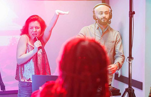 Group of people singing karaoke and having fun at a party.