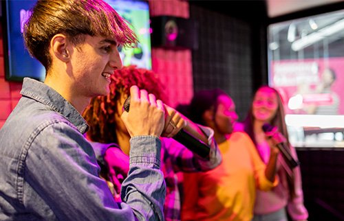 Man singing into microphone on stage at karaoke party.
