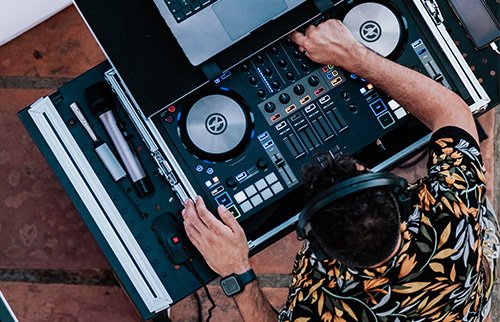 DJ using turntables and mixing console at a live event.